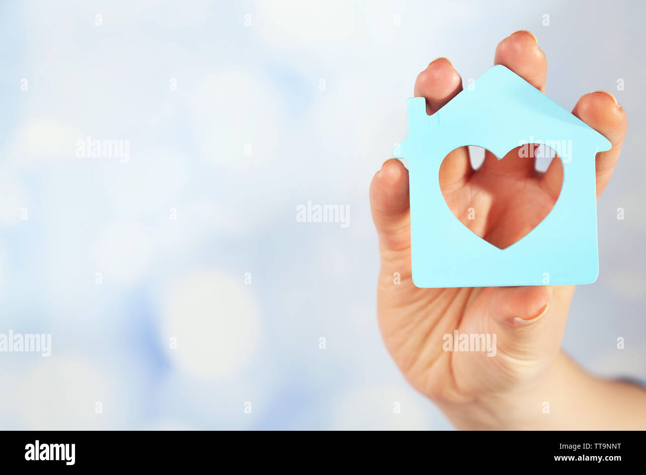Female hand with model of house on blurred background Stock Photo - Alamy