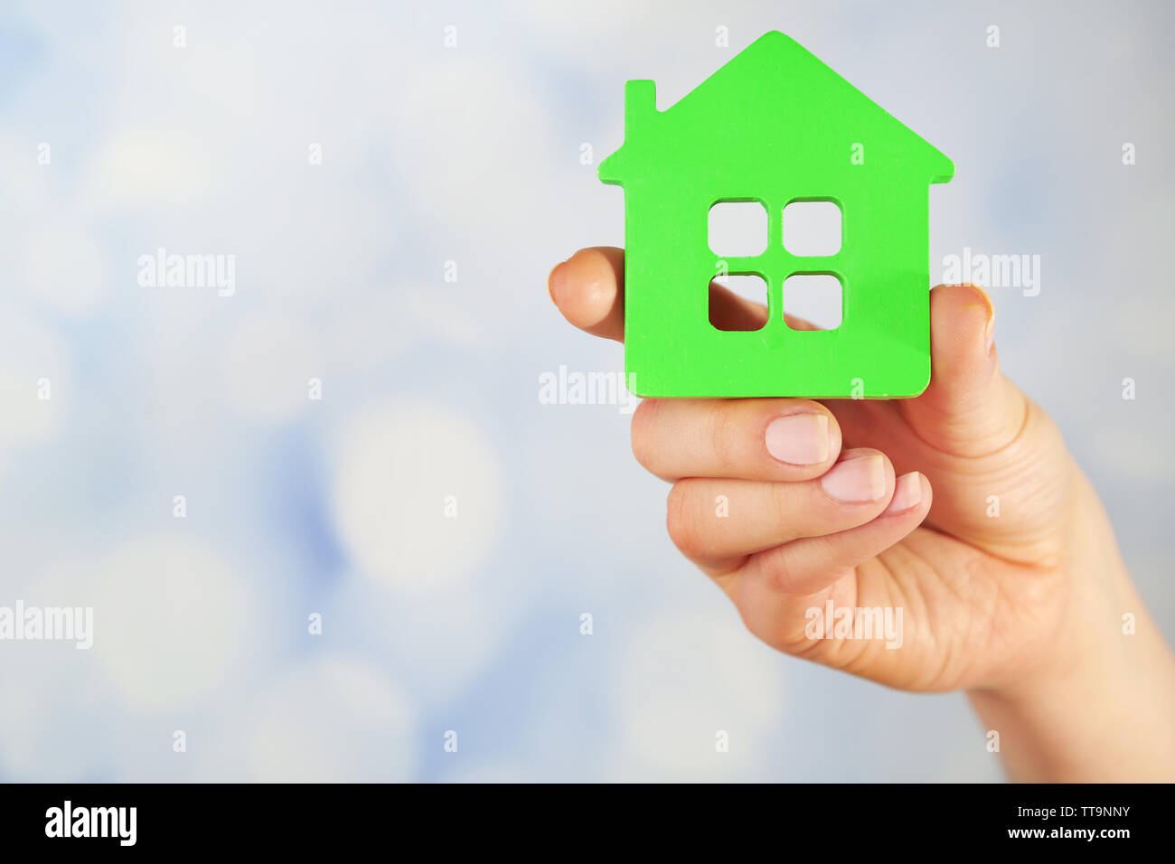 Female hand with model of house on blurred background Stock Photo - Alamy