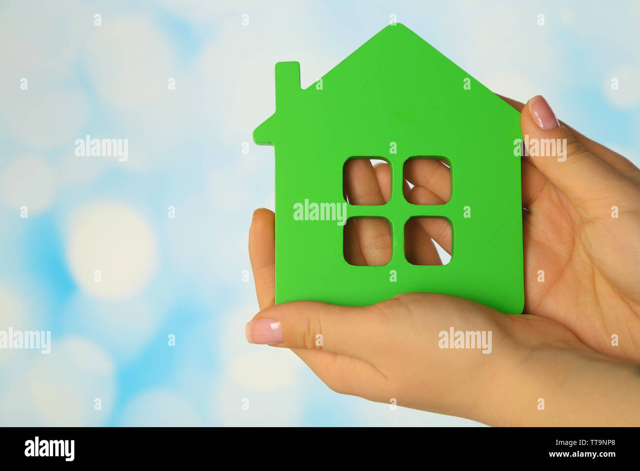 Female hands with model of house on blurred background Stock Photo - Alamy