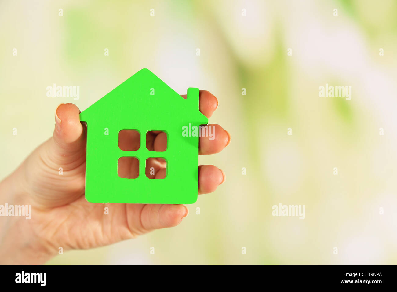 Female hand with model of house on blurred background Stock Photo - Alamy