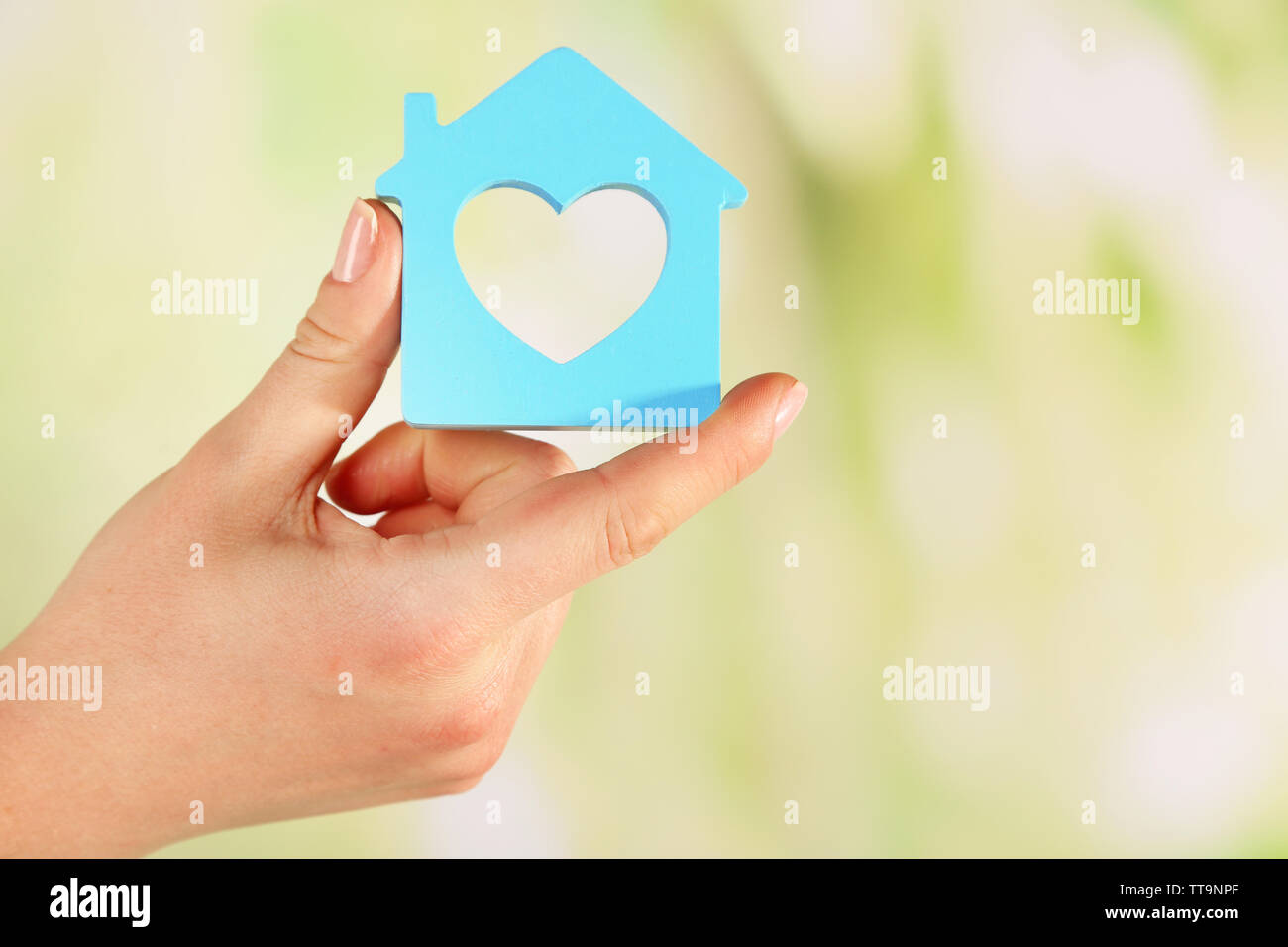 Female hand with model of house on blurred background Stock Photo - Alamy