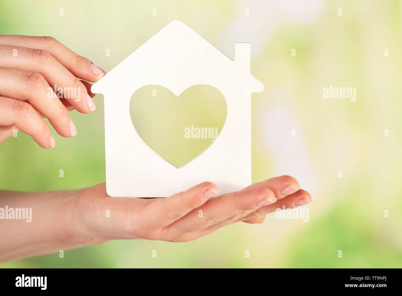 Female hands with model of house on blurred background Stock Photo - Alamy