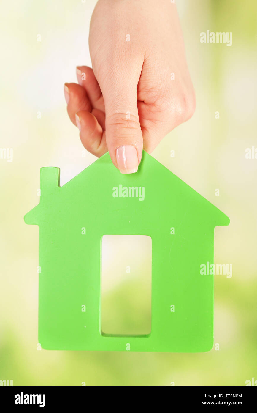 Female hand with model of house on blurred background Stock Photo - Alamy