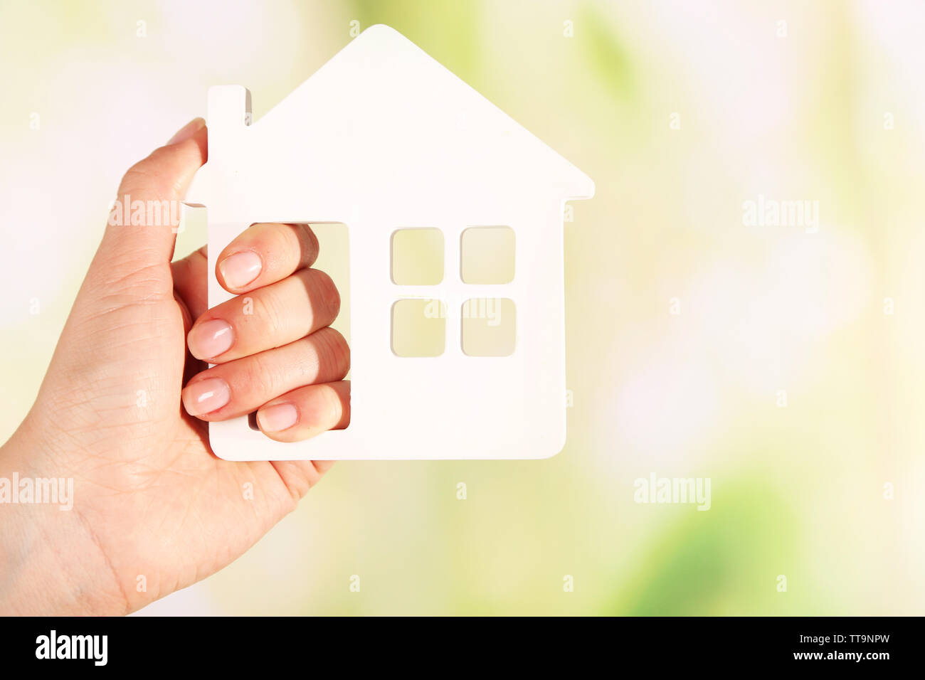 Female hand with model of house on blurred background Stock Photo - Alamy