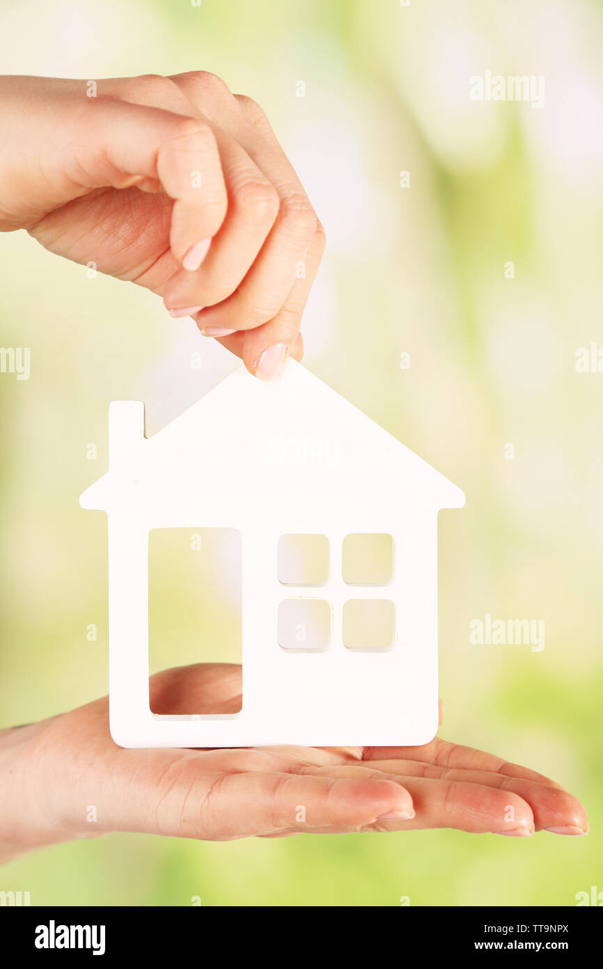 Female hands with model of house on blurred background Stock Photo - Alamy