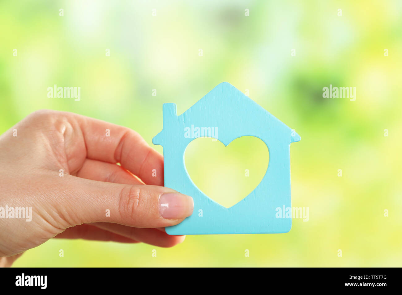 Female hand holding model of house on bright background Stock Photo - Alamy