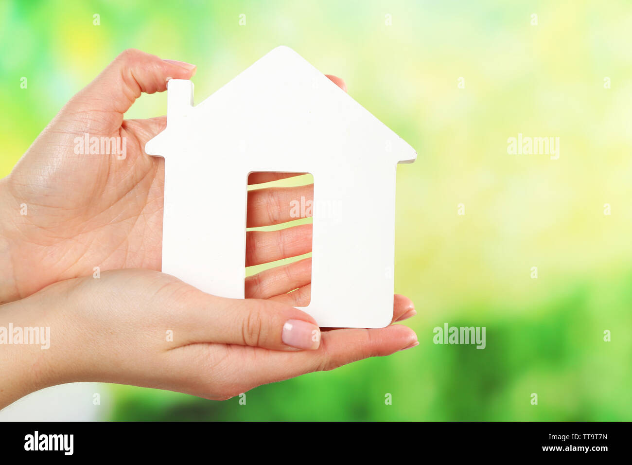 Female hands holding model of house on bright background Stock Photo ...