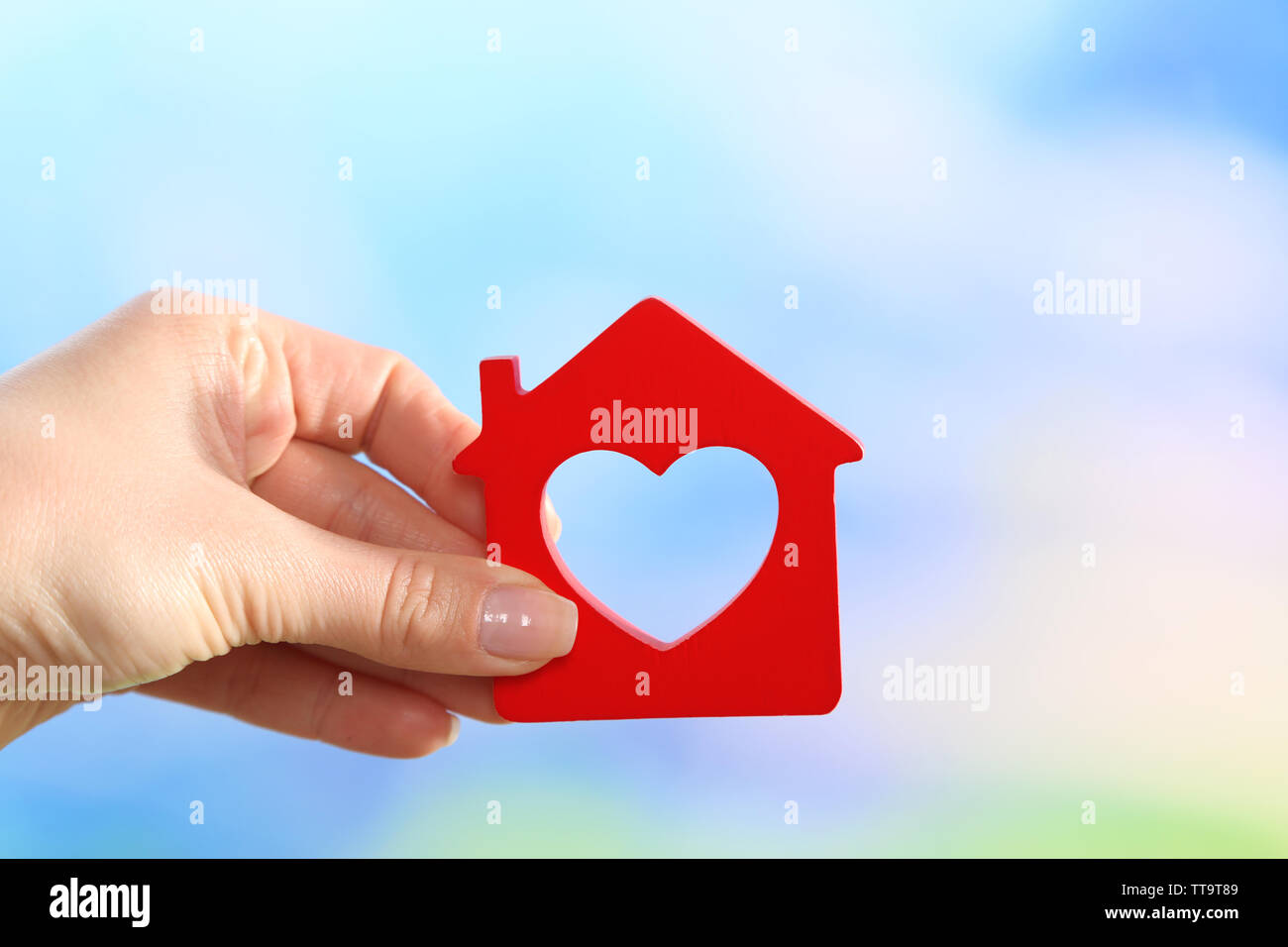 Female hand holding model of house on bright background Stock Photo - Alamy