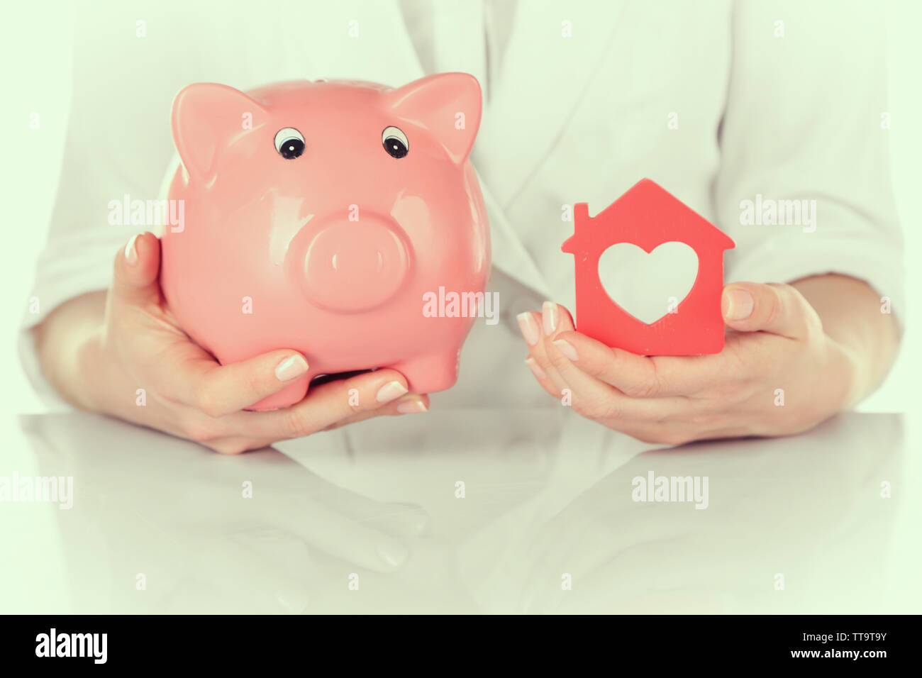 Woman holding model of house and piggy bank close up Stock Photo - Alamy