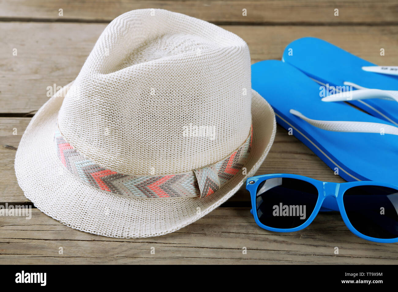 Sunglasses, flip flops and hat wooden background Stock Photo - Alamy