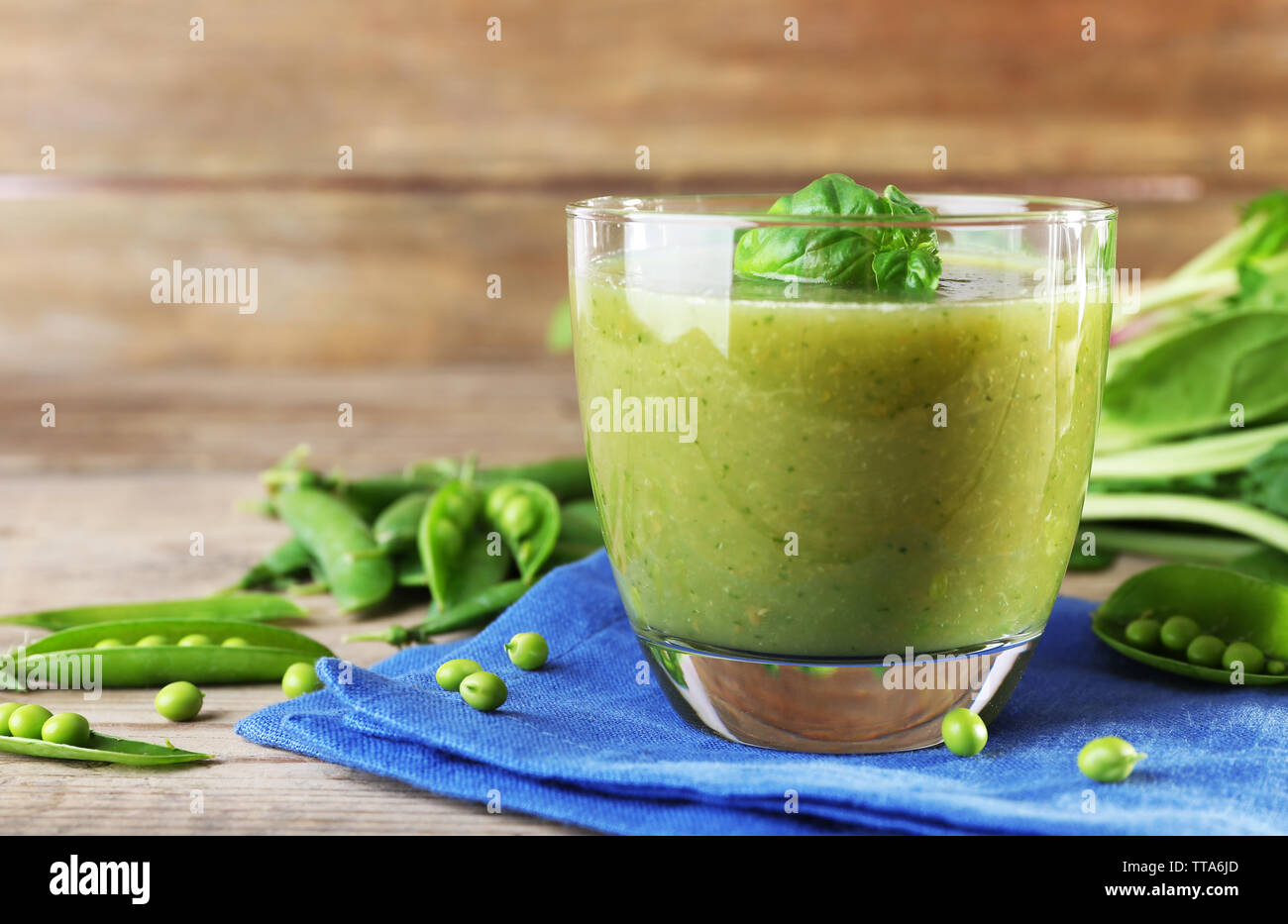Glass of green healthy juice with spinach and peas on table close up ...