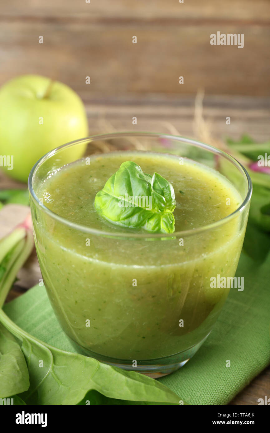 Glass of green healthy juice with spinach and apple on table close up ...