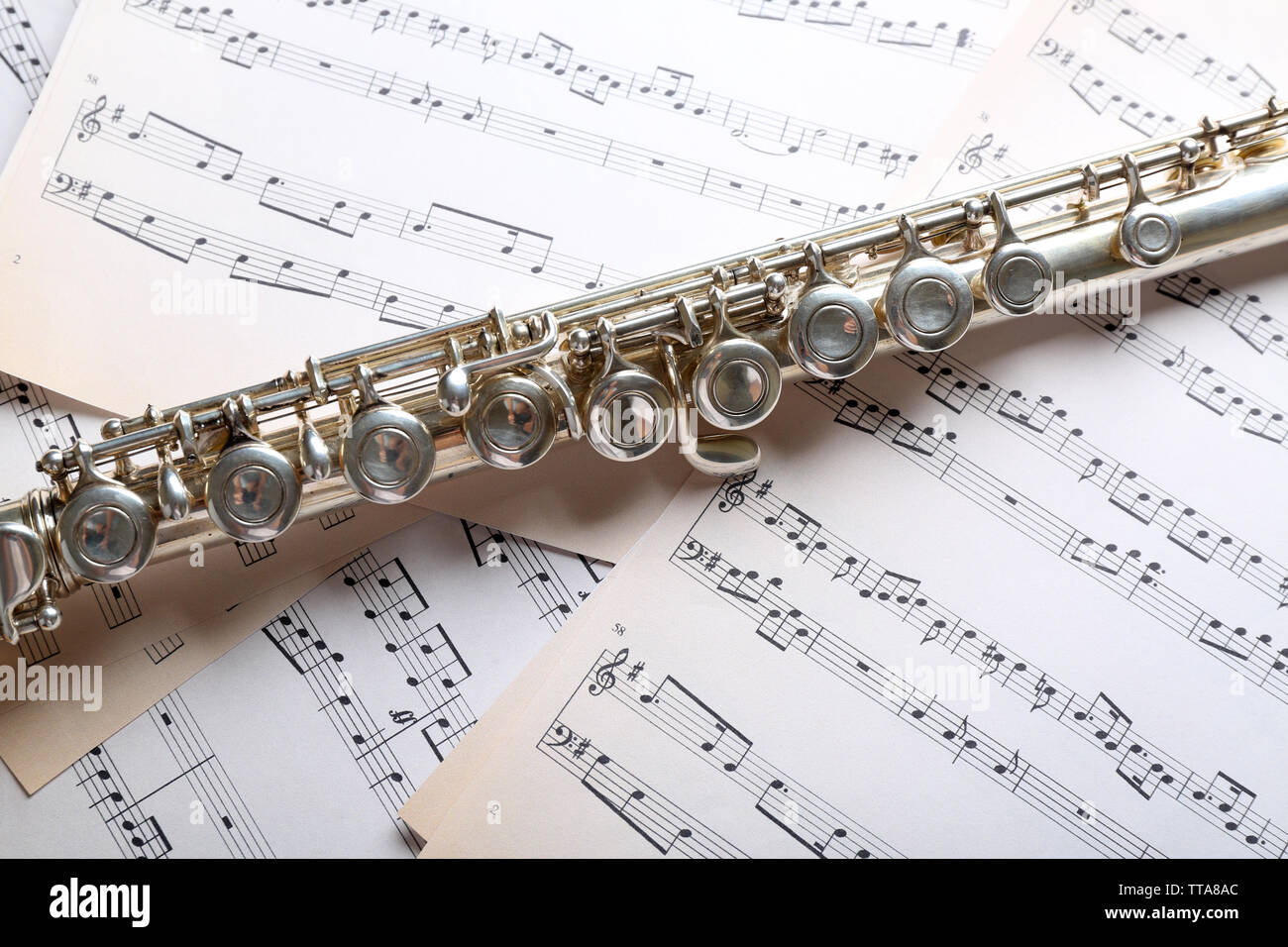 Silver flute on music notes background Stock Photo - Alamy