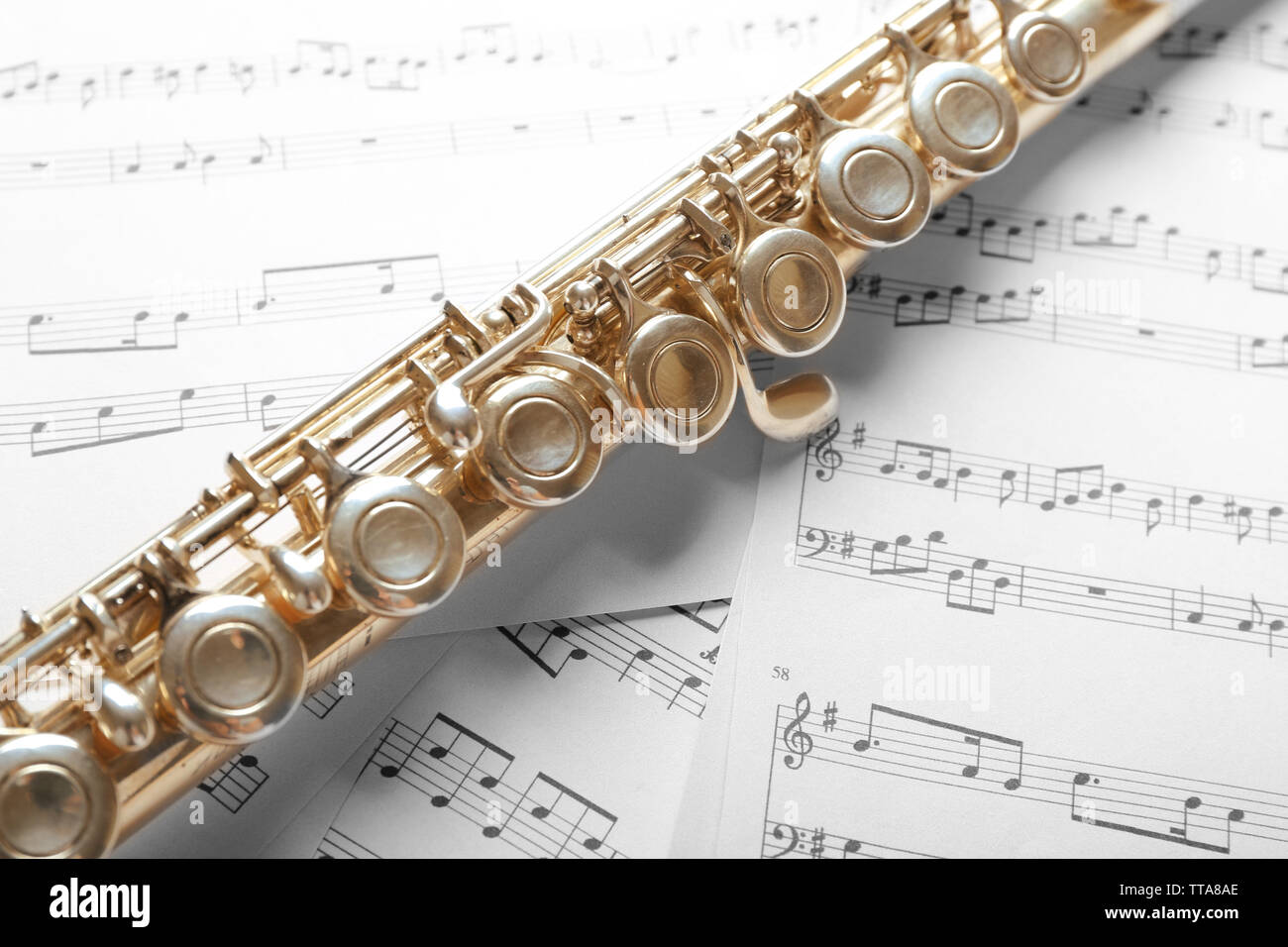 Silver flute on music notes background Stock Photo - Alamy
