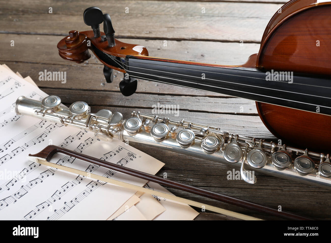 Flute and violin with music notes on wooden table close up Stock Photo
