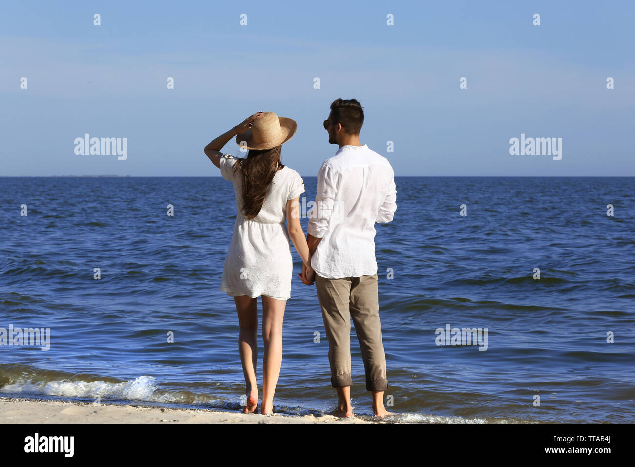 Young couple holding hands on beach Stock Photo - Alamy