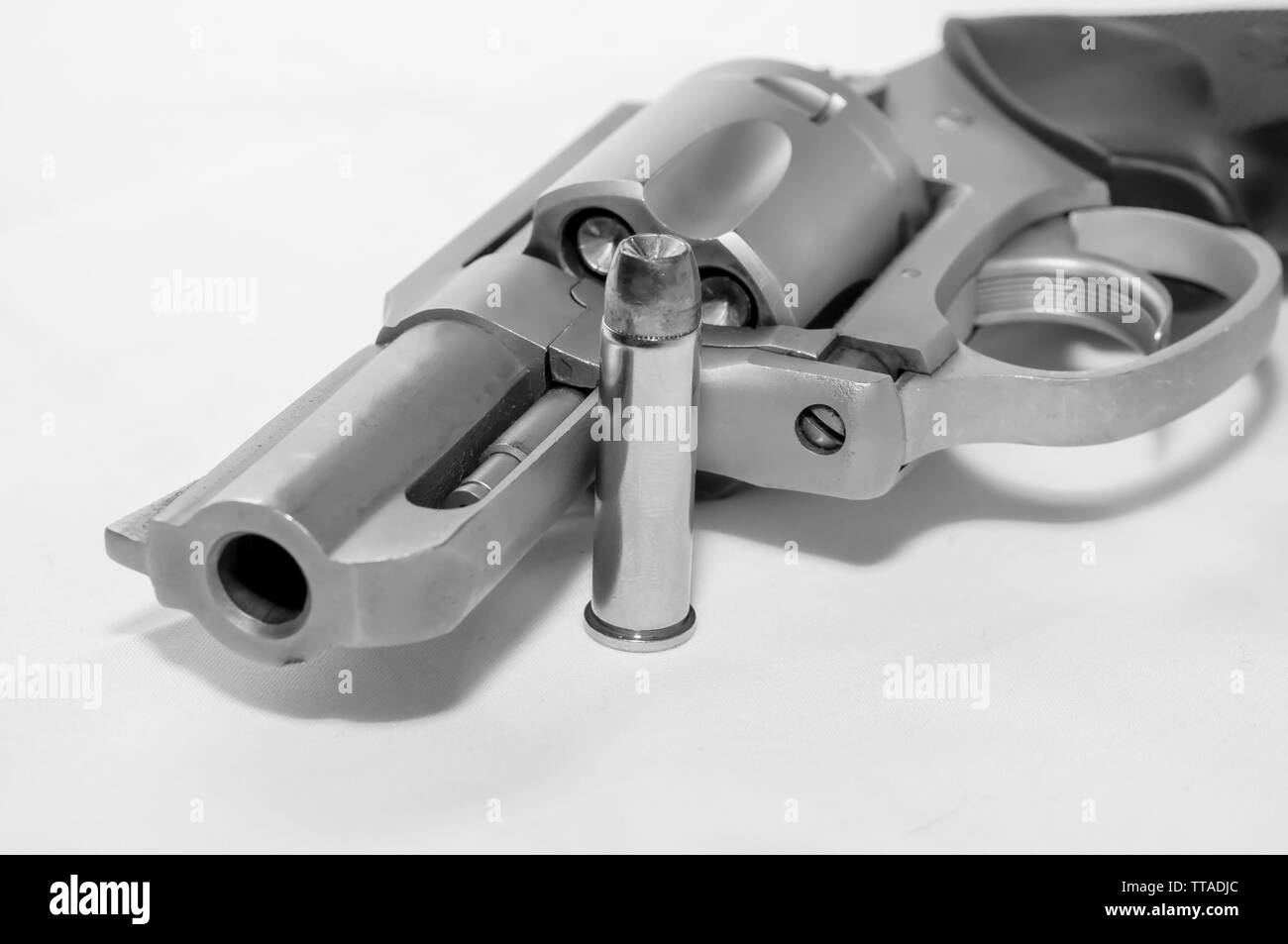A loaded 357 stainless steel revolver with a hollow point bullet next to it shot in black and white Stock Photo