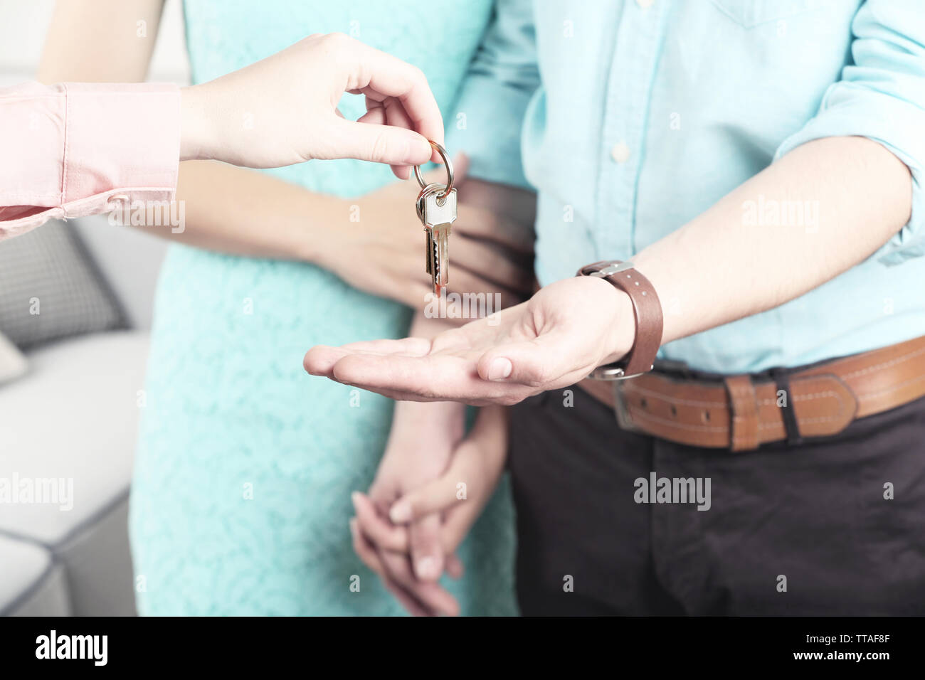 Real estate agent giving keys to young couple Stock Photo - Alamy