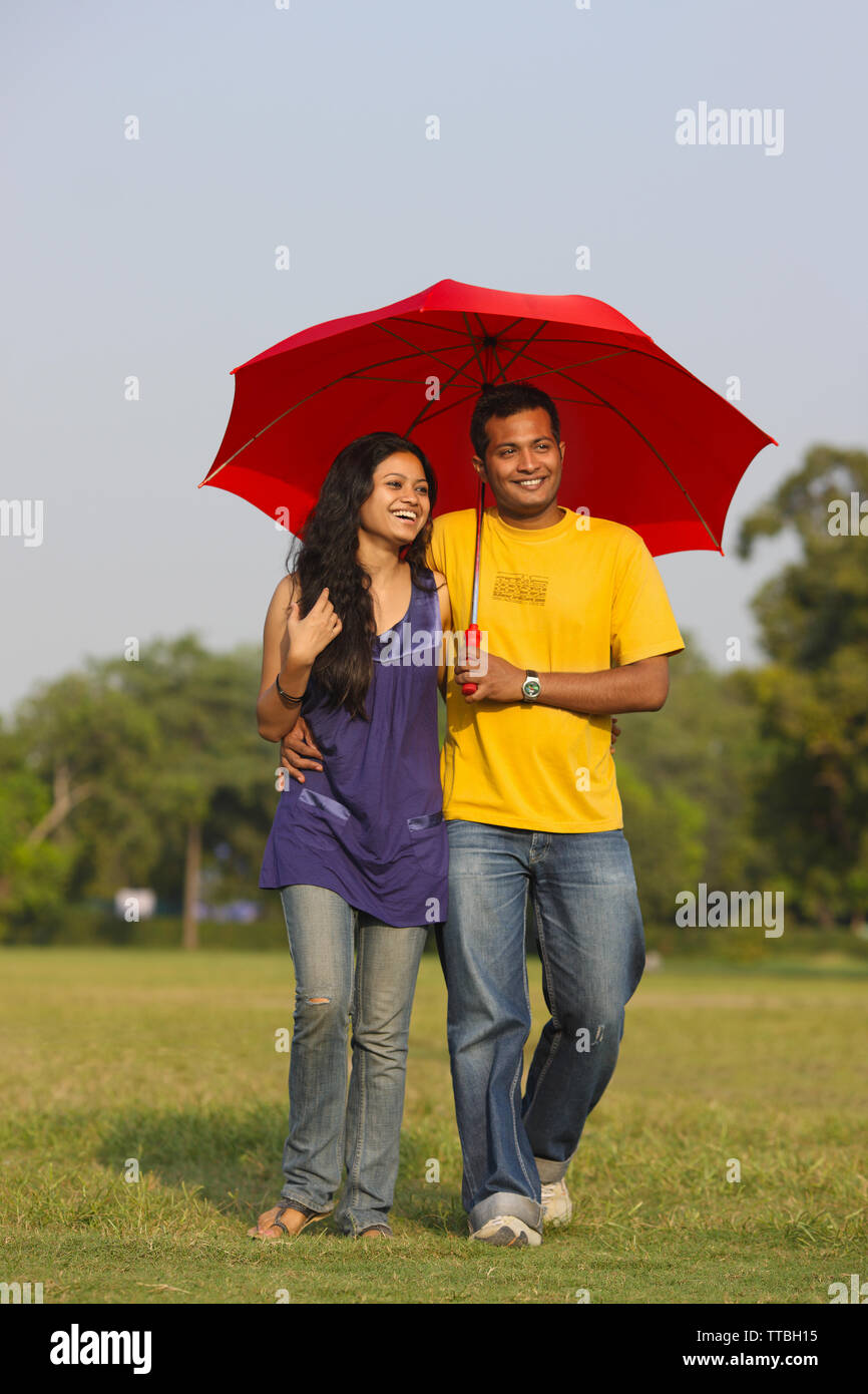 Couple walking together under an umbrella and smiling Stock Photo - Alamy