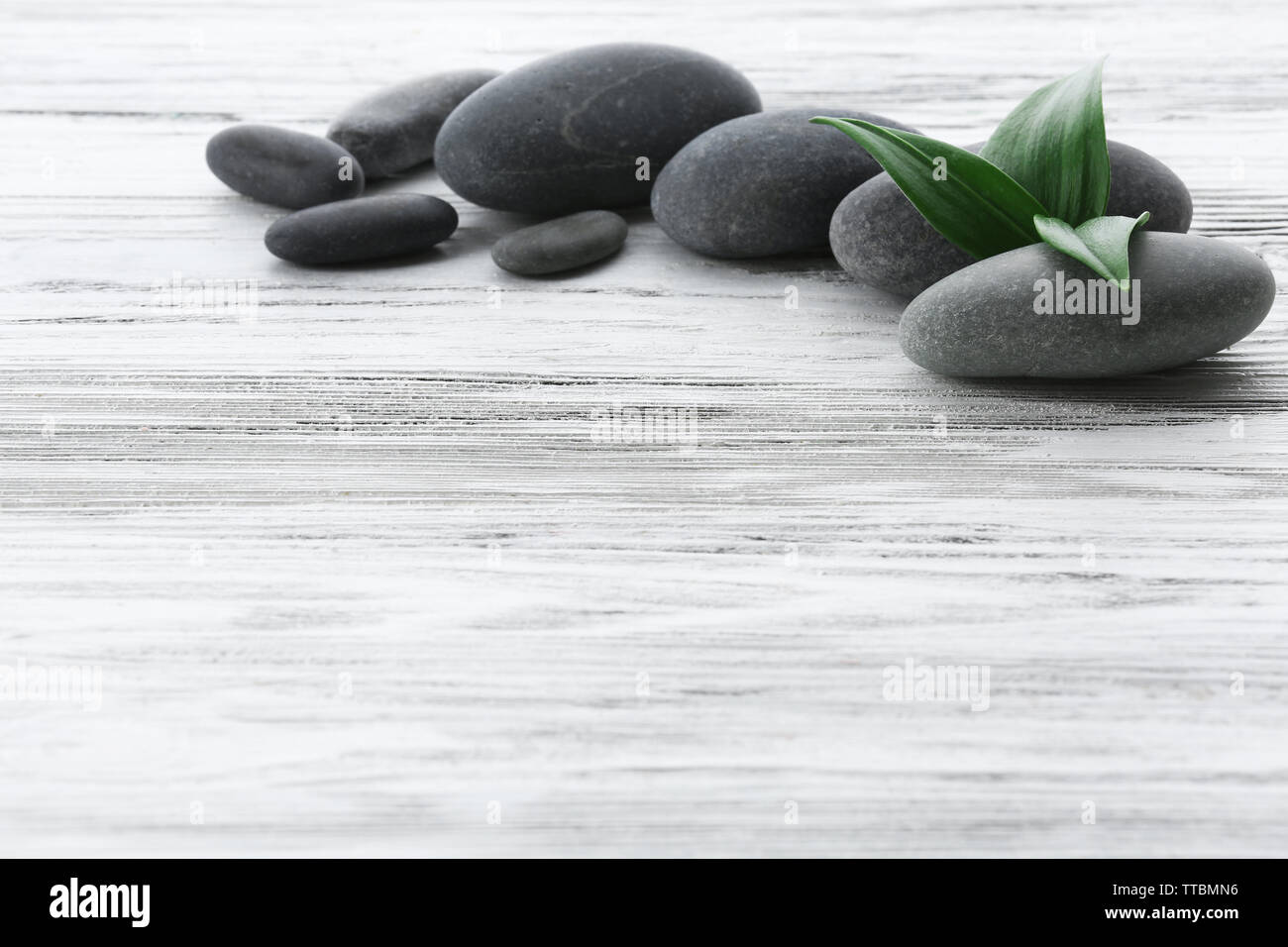 Spa stones with green leaves on wooden background Stock Photo - Alamy