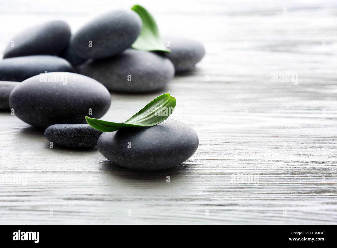 Spa stones with green leaves on wooden background Stock Photo - Alamy