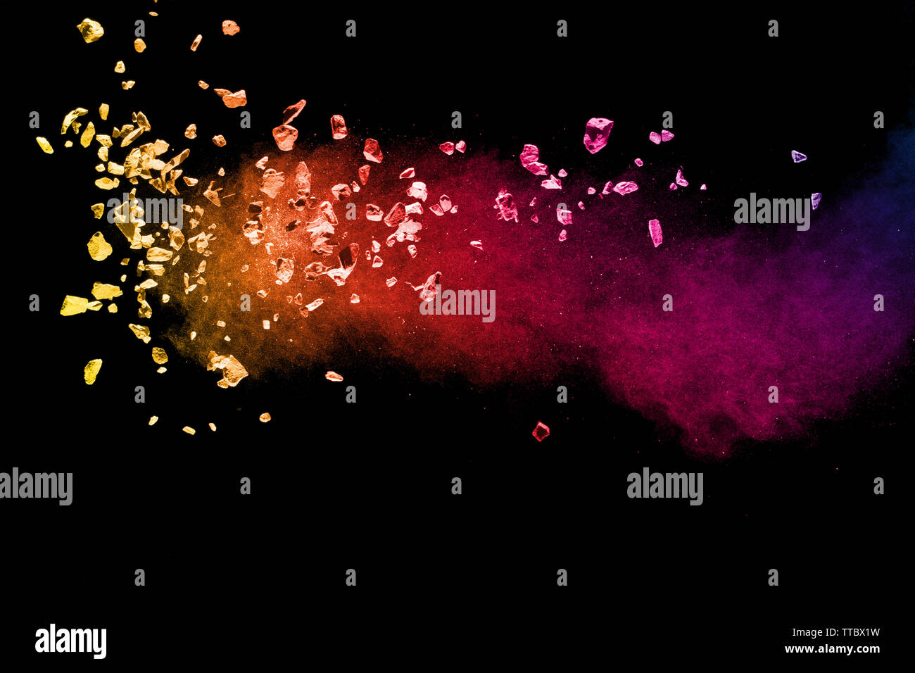 Split debris of colored stone with dust exploding against black background. Stock Photo
