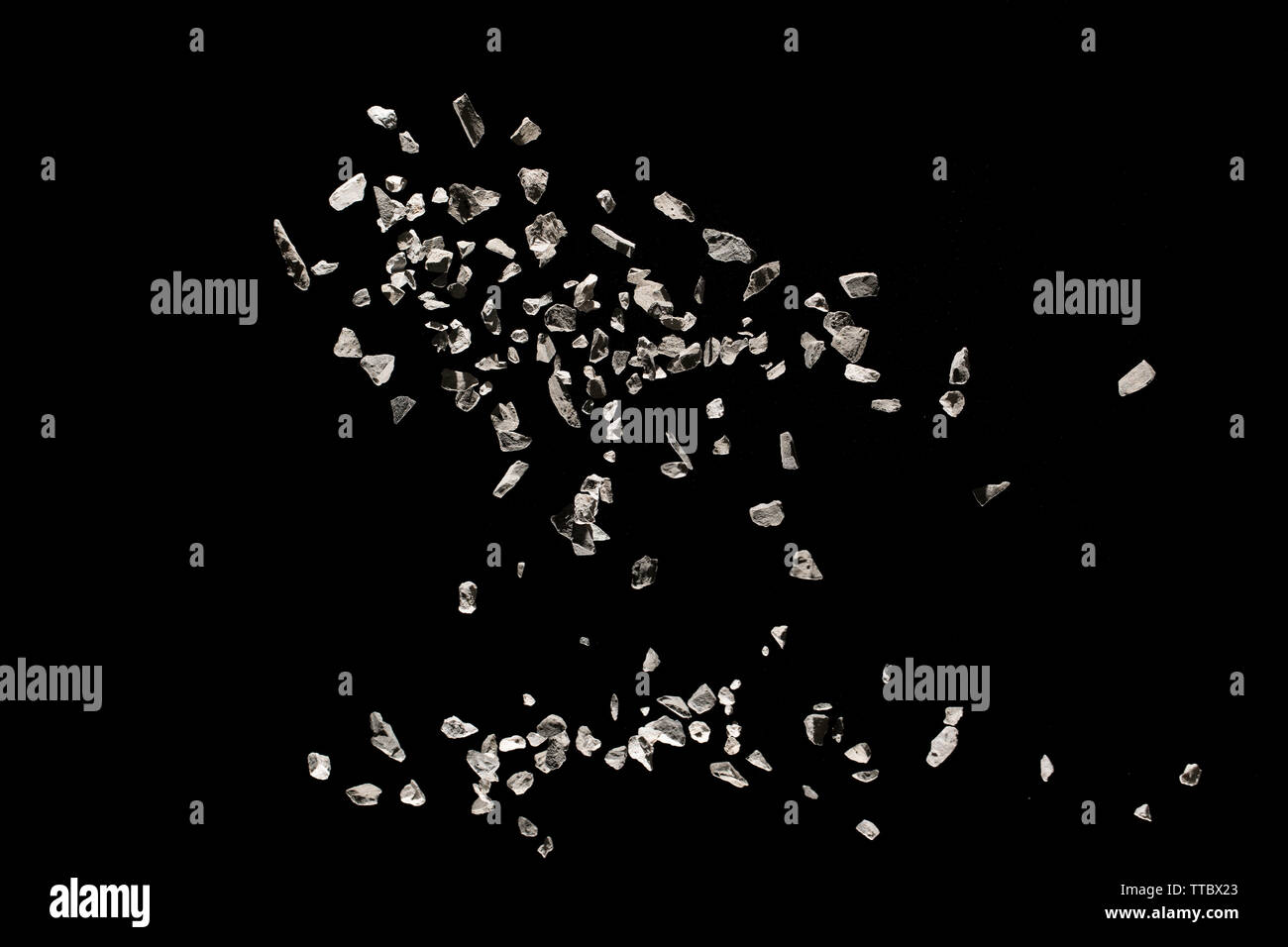 Split debris of stone exploding against black background. Stock Photo