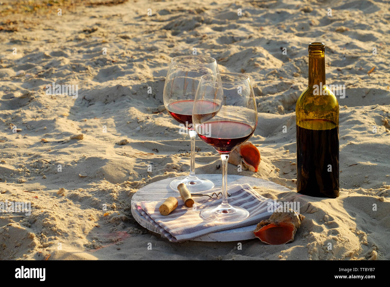 Wine bottle and glasses on sand background Stock Photo - Alamy