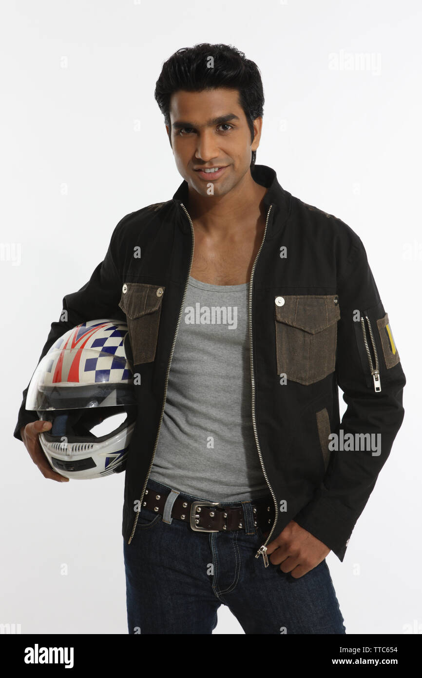 carry helmet on motorcycle arm Biker holding a helmet under the arm and smiling Stock Photo