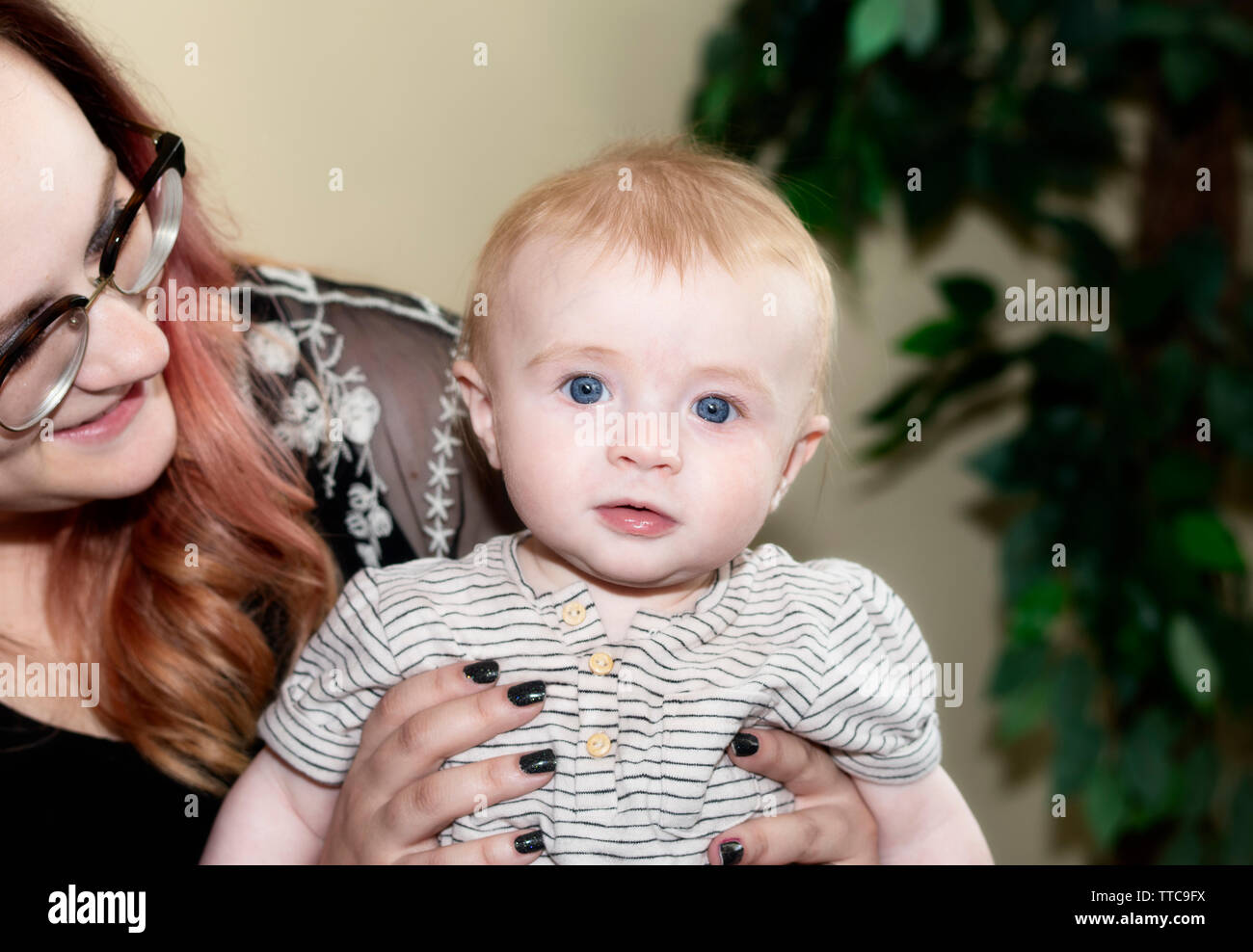 Red-headed Baby Boy Held by Mother Looking Straight at Camera with Big Blue Eyes Stock Photo
