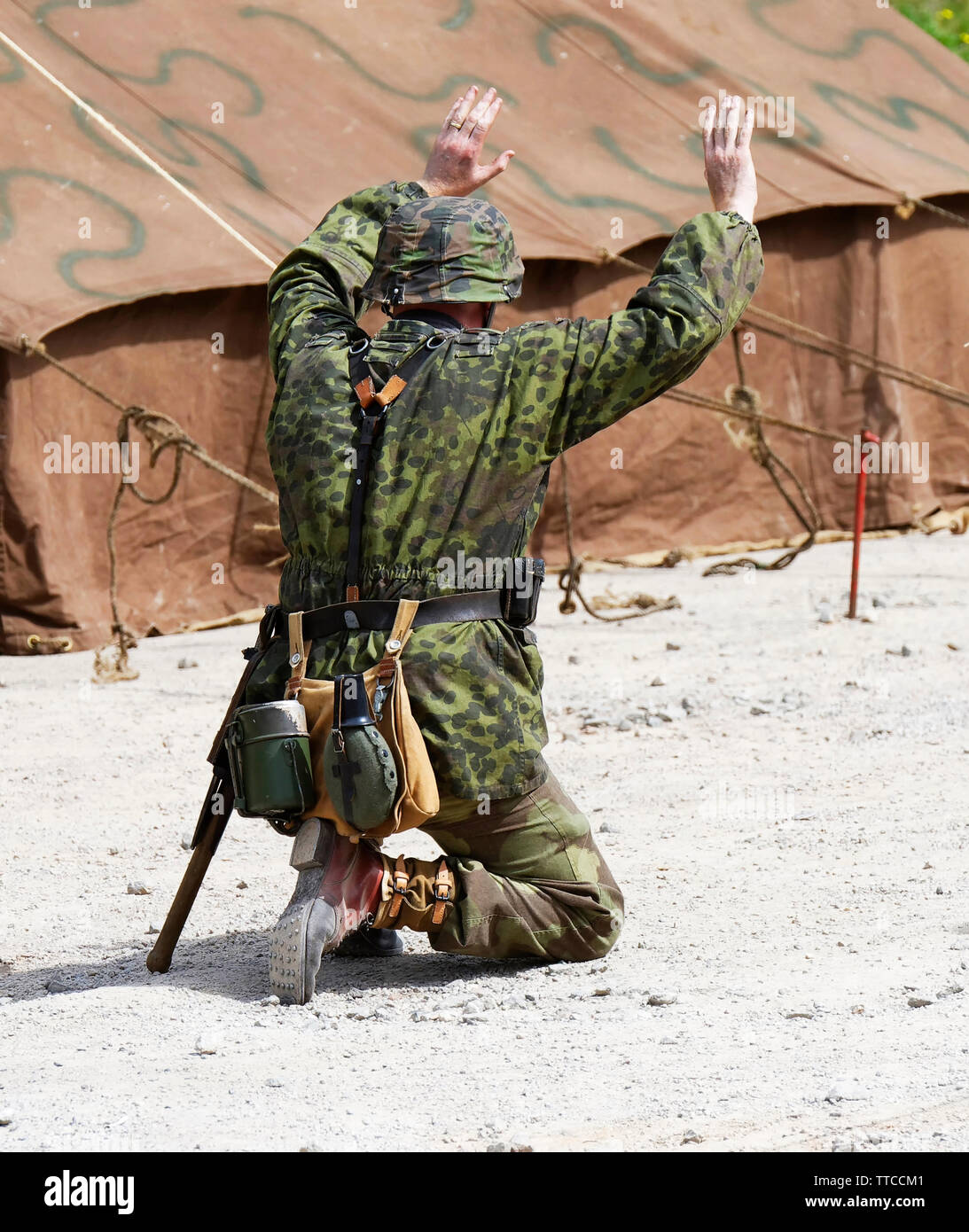 A reenactor dressed as a German World War Two Waffen SS Soldier surrendering Stock Photo