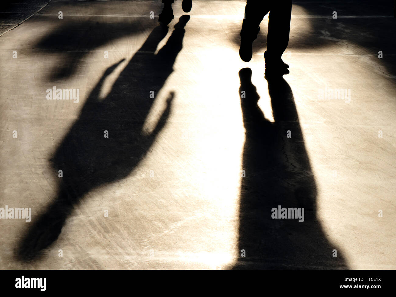 Blurry reflection shadow silhouette of  men walking on pedestrian road in sunset Stock Photo