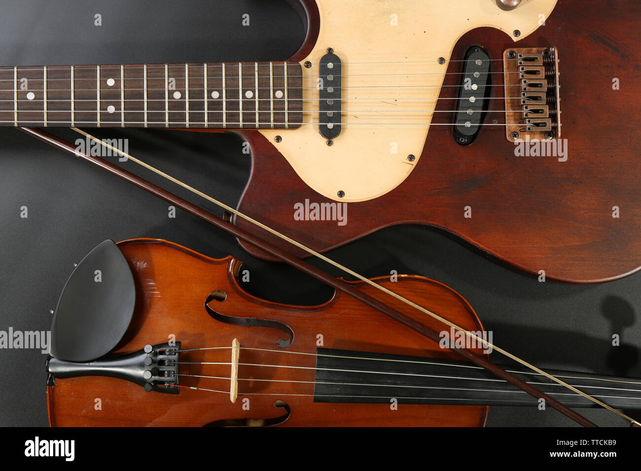 Electric guitar and violin on grey background Stock Photo - Alamy