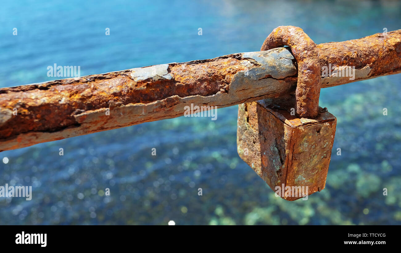 A very old and rusty love lock or padlock on a section of the chain ...