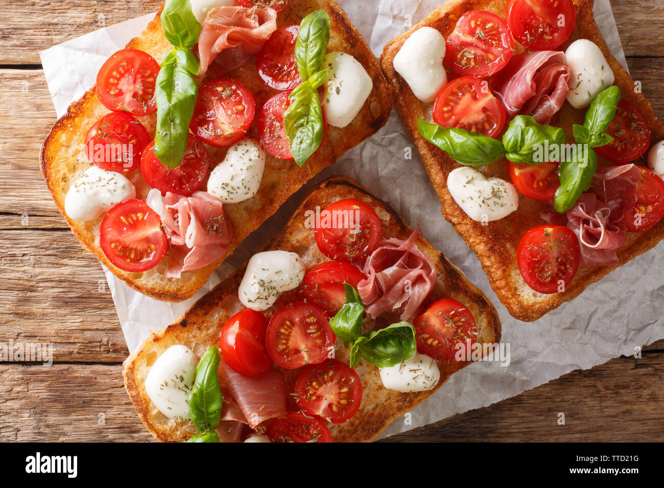 Ciabatta sandwiches with mozzarella, tomatoes, ham and basil close-up on the table. Horizontal top view from above Stock Photo