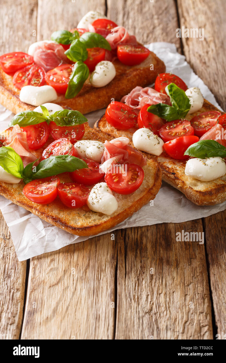 Italian sandwiches with mozzarella, tomatoes, prosciutto and basil close-up on the table. vertical Stock Photo
