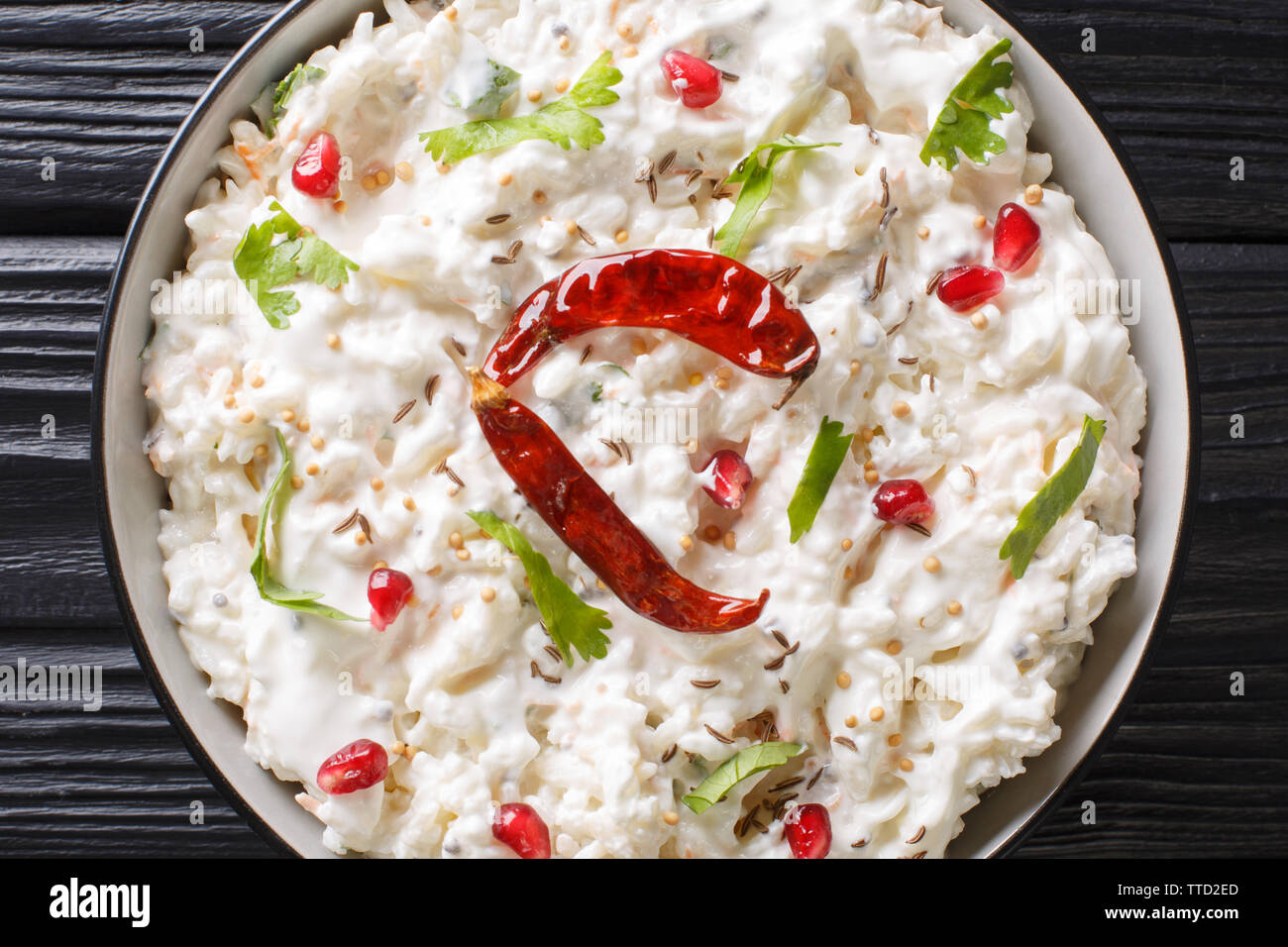 Indian Curd rice with carrots, pomegranate and with additional tempering of spices close-up in a plate on the table. horizontal top view from above Stock Photo