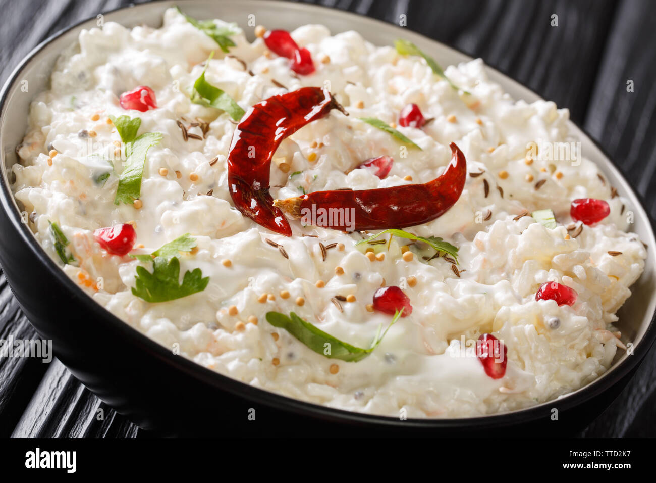 Curd rice or Thayir Sadam is a delicious south Indian recipe where cooked rice is mixed with curd and a tempering is done to it closeup in a plate on Stock Photo