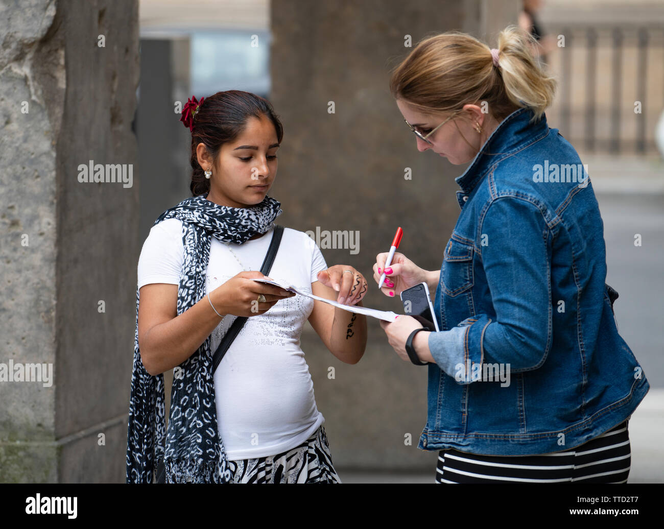 Tourist signing fake petition before handing over money donation in common scam operated by gangs of women in Berlin, Germany Stock Photo