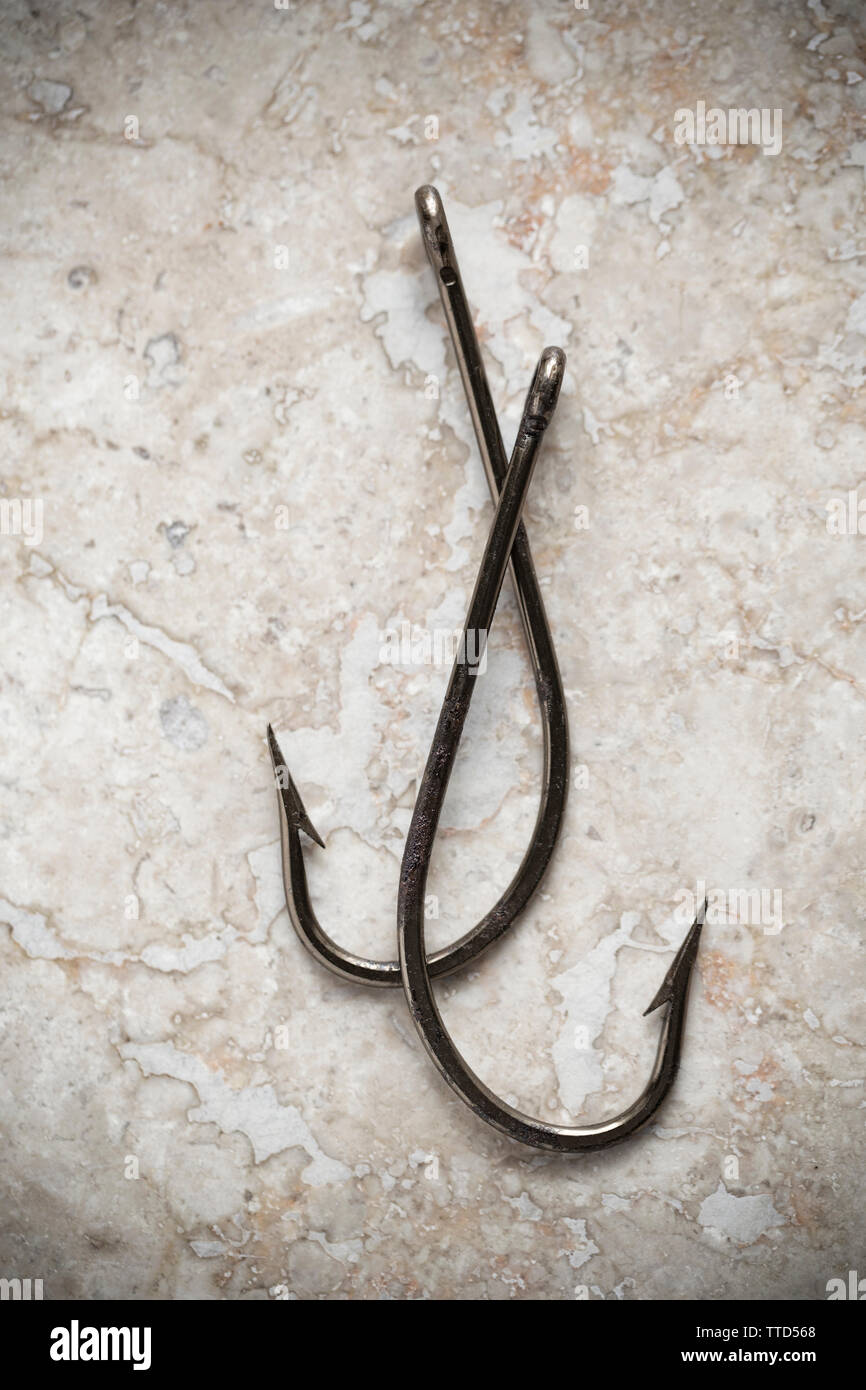 Two large seafishing hooks displayed on a stone background. Picture desaturated. Dorset England UK GB Stock Photo