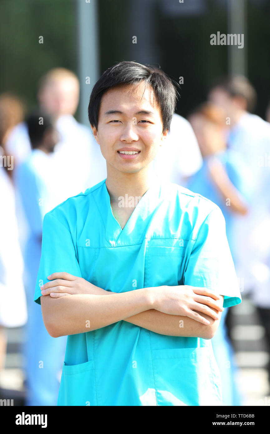 Young smiling doctor standing against group of medical workers Stock Photo