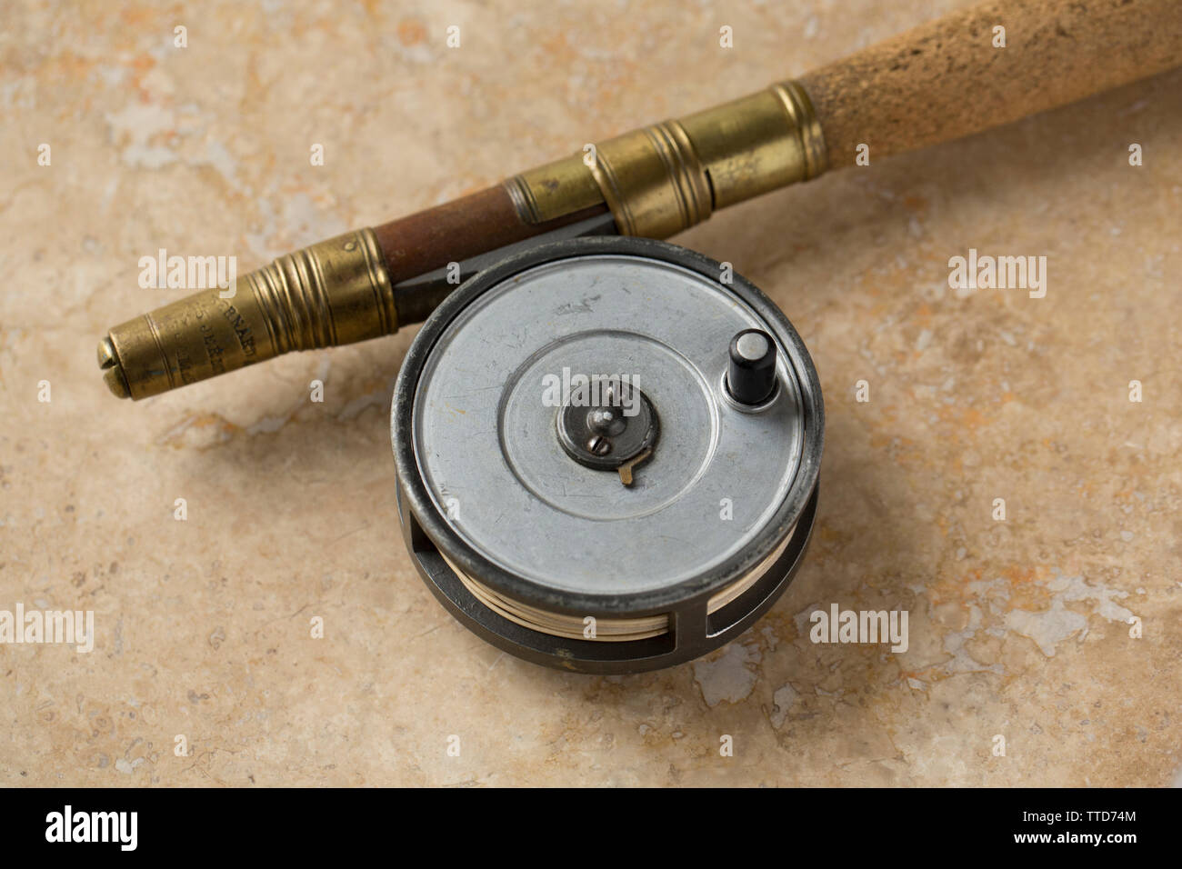 An old Hardy Hydra fly fishing reel attached to an old Bernard & Son split cane fishing rod. Photographed on a light stone background. From a collecti Stock Photo