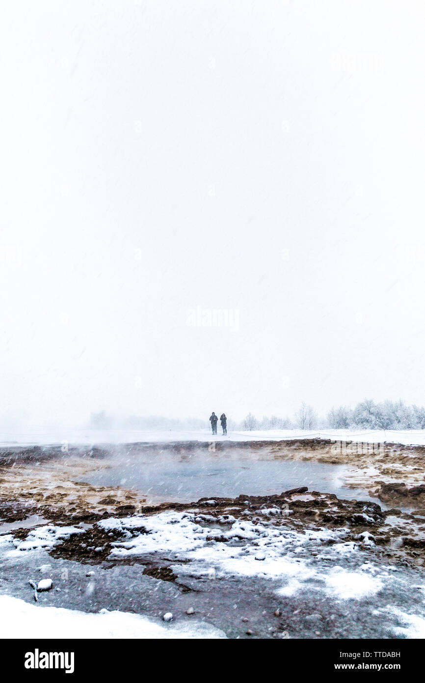 Tourists waiting in cold snowy weather for a geyser eruption, Geysir, Iceland Stock Photo