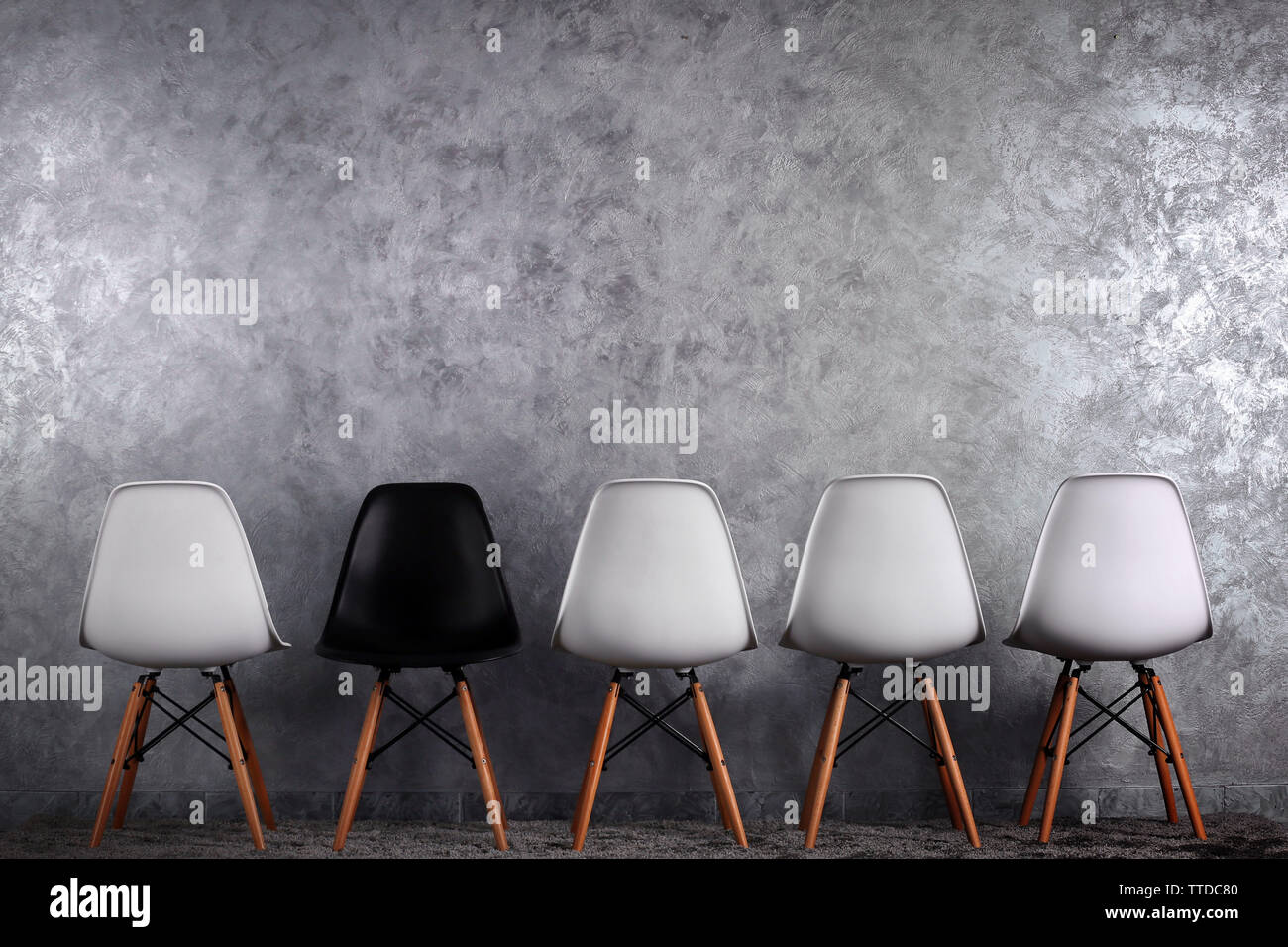 Stylish conception with white and black chairs on grey background Stock Photo