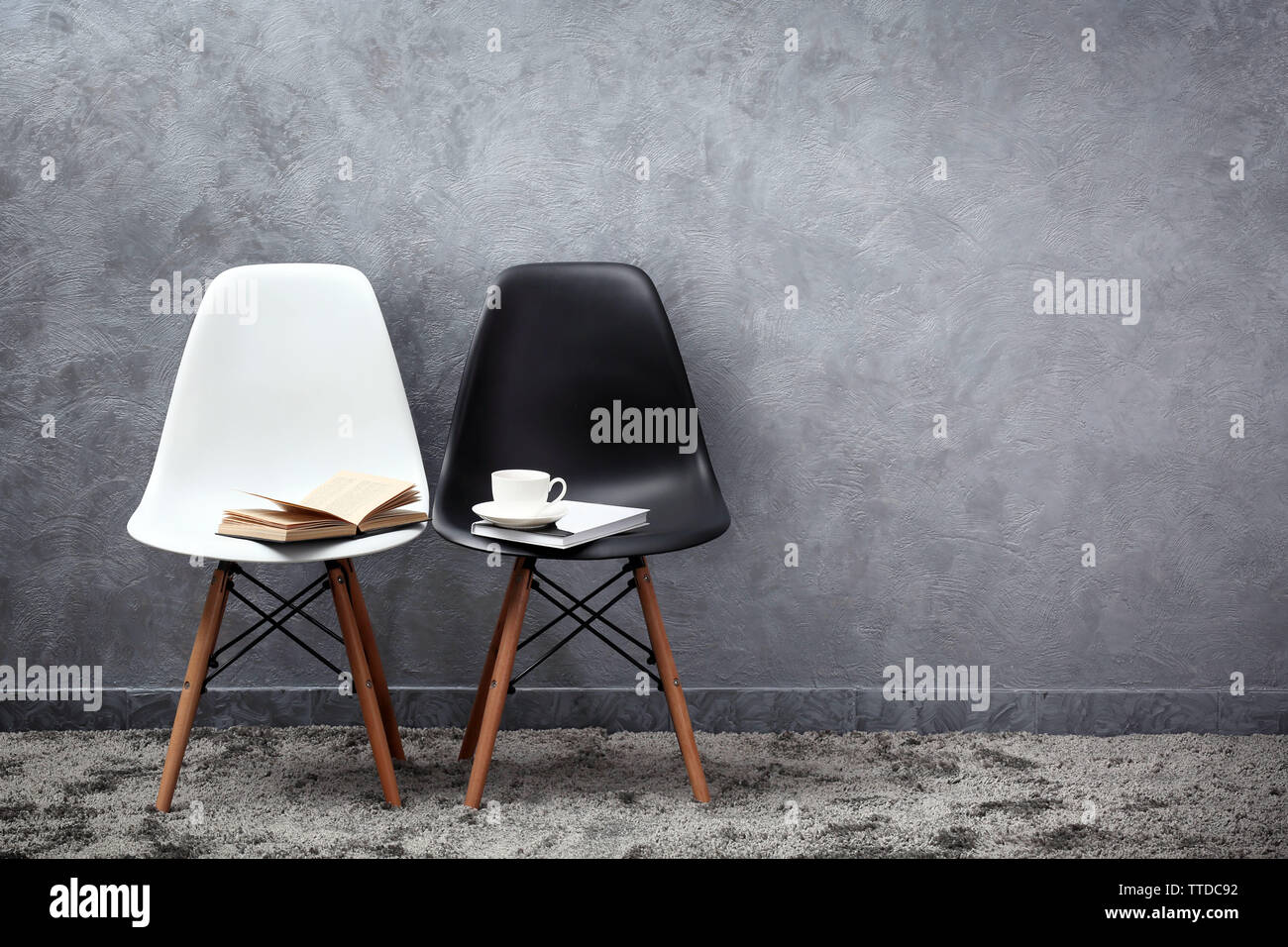 Stylish conception with white and black chairs on grey background Stock Photo