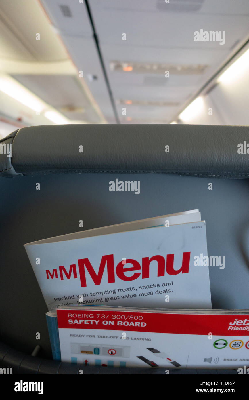 Back of the passenger seat on a  Boeing 737 showing magazine rack with flight menu and safety card Stock Photo