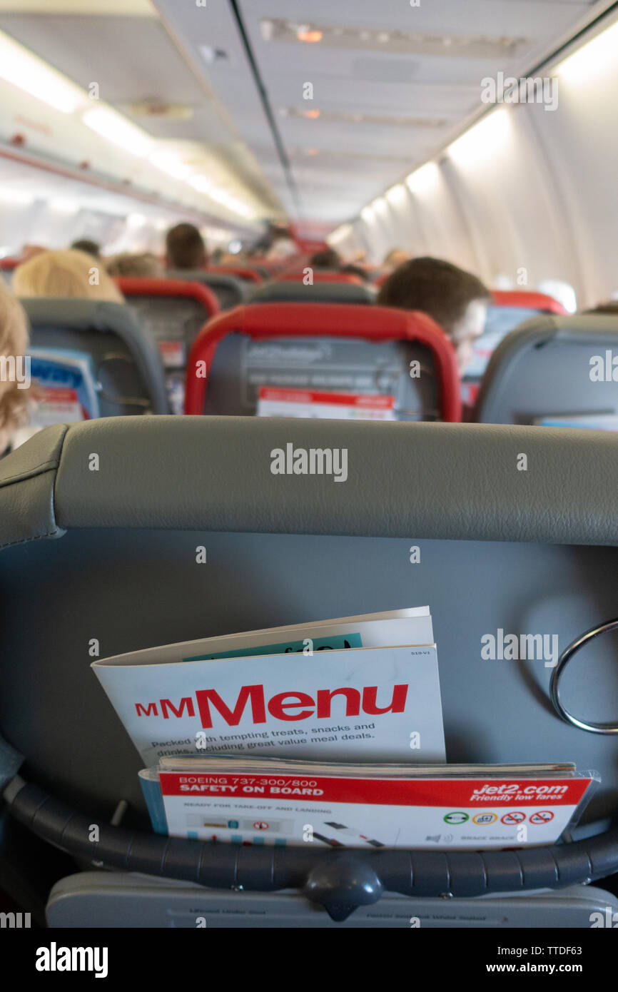 Back of the passenger seat on a  Boeing 737 showing magazine rack with flight menu and safety card Stock Photo