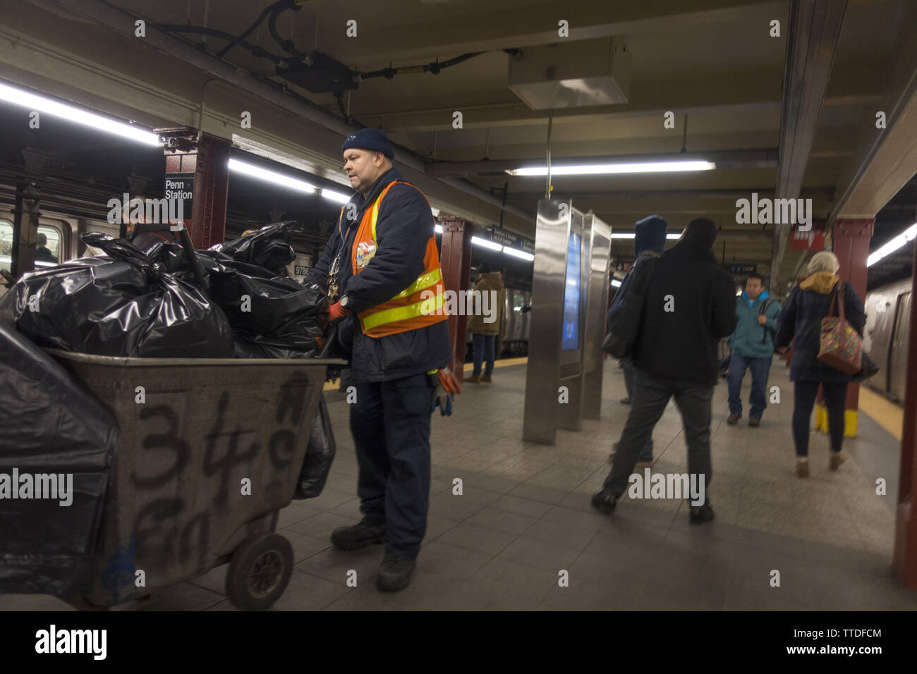 MTA custodial worker emptying garbage on the  34th Street subway train platform at Penn Station in Manhattan. Stock Photo