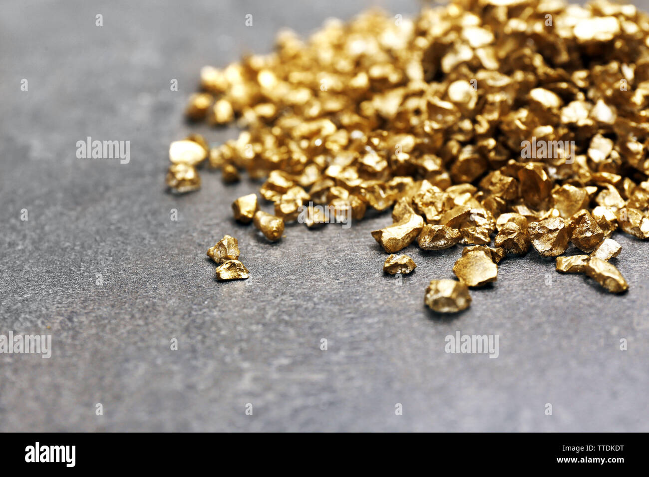 A pile of Gold nugget grains, on cement background Stock Photo - Alamy
