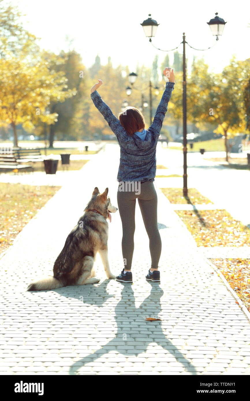 Happy young woman walking with her dog in park Stock Photo - Alamy